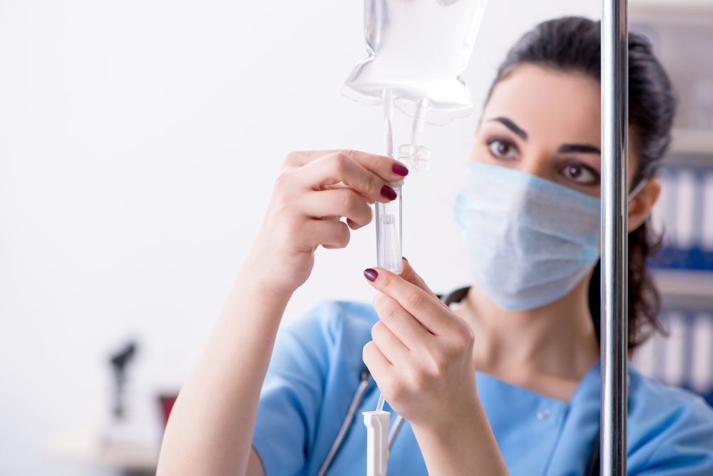 Nurse preparing IV vitamin drip for patient.