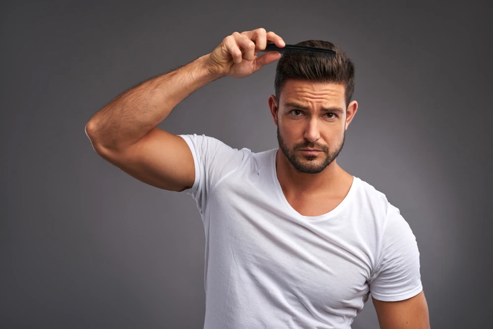 Man confidently styling hair after successful hair restoration.